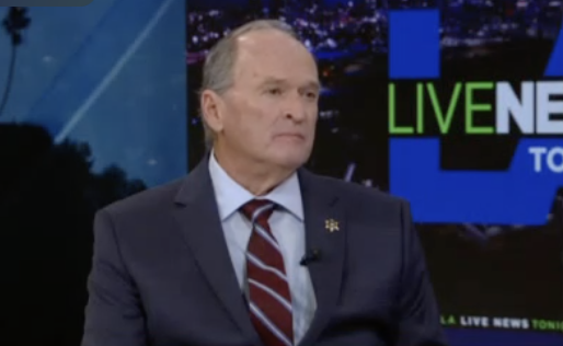 Man in suit during live news broadcast.